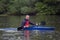 Young athletic man sits in a sports kayak boat smiling on a wide