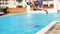 Young athletic man in swim shorts running and jumping spinning to the swimming pool. Slowmotion shot.