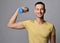 Young athletic man in t-shirt works out with weights, holds a dumbbell in hand. Healthy lifestyle