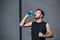 Young athletic man in tanktop holding a jumping rope and drinking water from