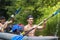 Young athletic men in boat rowing oars along the river on summer day. Canoe. Friends are swimming in a kayak