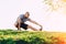 Young athletic runner doing stretching exercise, preparing for workout in the park. sunset