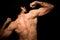 Young athletic shirtless man posing on black background