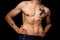 Young athletic shirtless man posing on black background