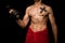 Young athletic shirtless man working out on black background