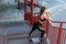 Young athletic slim beautiful woman have a rest and standing on stairs after doing cardio interval training in black fashionable