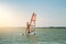 Young athletic slim girl sails on a windsurf board in the open sea on summer vacation at resort. Windsurfing