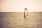 Young athletic slim girl sails on a windsurf board in the open sea on summer vacation at resort. Windsurfing