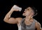 Young athletic sport man thirsty drinking water holding bottle pouring fluid on sweaty face