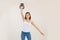 Young athletic woman lifting up kettlebell and putting down arm, white background. Keeping fit by strength workout and