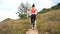 Young athletic woman running on mountain trail. Sunset Workout in Nature. Fit girl in pink top run.