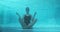 Young athletic woman sitting in lotus pose underwater in blue outdoor swimming pool