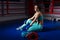 Young athletic woman sitting near lying boxing gloves and helmet