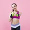 Young athletic woman, with a smile, in a bright top, trains punches, keeps dumbbells on weight, on a pink background.