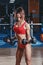 young athletics girl posing with barbell on her shoulders