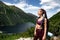 Young attarctive brunette girl in red sportswear in front of beautiful mountains lake panorama, active lifestyle concept