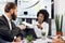 Young attractive African businesslady, showing some paper with infographic charts to her bearded high-skilled Caucasian