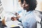 Young attractive african woman smiling and looking at the camera in modern office.Coworkers teamwork concept. Horizontal, blurred