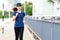 Young attractive asian runner woman running in urban city street or foot path way listen to music wearing blue or black sporty