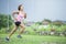 Young attractive Asian sport runner woman running in the jungle smiling happy in training workout on herb background in fitness