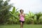 Young attractive Asian sport runner woman running in the jungle smiling happy in training workout on herb with palm trees on the b