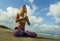 Young attractive and athletic woman sitting in yoga lotus posture and namaste hands position at beautiful beach doing relaxation