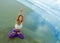 Young attractive and athletic woman sitting in yoga lotus posture and namaste hands position at beautiful beach doing relaxation