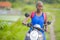 Young attractive backpacker tourist afro American black woman riding motorbike happy in beautiful Asia countryside along green ric