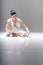 Young attractive ballerina sitting on the floor working with her pointed ballet shoes