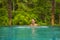 Young attractive and beautiful Asian Korean woman relaxing happy at tropical beach resort swimming at jungle infinity pool