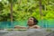 Young attractive and beautiful Asian Korean woman relaxing happy at tropical beach resort swimming at jungle infinity pool