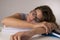 Young attractive and beautiful tired student girl leaning on school books pile sleeping tired and exhausted after studying