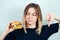 Young and attractive blond woman in black T-shirt and measuring tape holding a high-calorie burger and showing thumbs