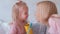 Young attractive blond woman kiss her little charming daughter in pink dresses with felt-pens