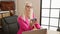 Young, attractive blonde woman, relaxing with business talk via smartphone and laptop at the office, exuding success and