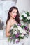 Young attractive bride with flowers indoors . Bride`s morning. Happy Bride waiting groom.