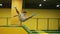 Young attractive brunete male springs over yellow barrier at professional trampoline. Youth, sport, gymnastics.