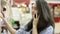 Young attractive brunette smiles happily and talks on the phone while browsing the shelf with products in supermarket