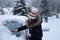 Young attractive brunette woman clearing snow off a car with a ice scraper in the winter.