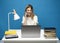 Young attractive business woman with a blond hair sitting at the table and working on a laptop and talking with a client