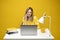 Young attractive business woman with a blond hair sitting at the table and working on a laptop and talking with a client