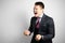 Young attractive businessman businessman in suit on gray background in rage, anger and madness