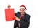 Young attractive businessman in Christmas Santa hat holding and pointing red shopping bag in December and New year sale