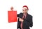 Young attractive businessman in Christmas Santa hat holding and pointing red shopping bag in December and New year sale