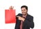 Young attractive businessman holding and pointing red shopping bag in sale concept performing as salesman