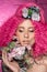 Young attractive caucasian girl model with curly bright pink hair, tattooed face and flowers woven into her hair. Photo in the