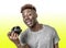 Young attractive and cool happy black afro American man holding digital reflex photo camera smiling excited isolated on yellow bac