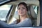 Young attractive coquettish caucasian woman in car flirting with pedestrian or other driver. Trendy and confident diverse woman be