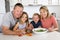 Young attractive couple mother and father preparing salad together with little son and young beautiful daughter in healthy vegetab