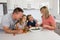 Young attractive couple mother and father preparing salad together with little son and young beautiful daughter in healthy vegetab